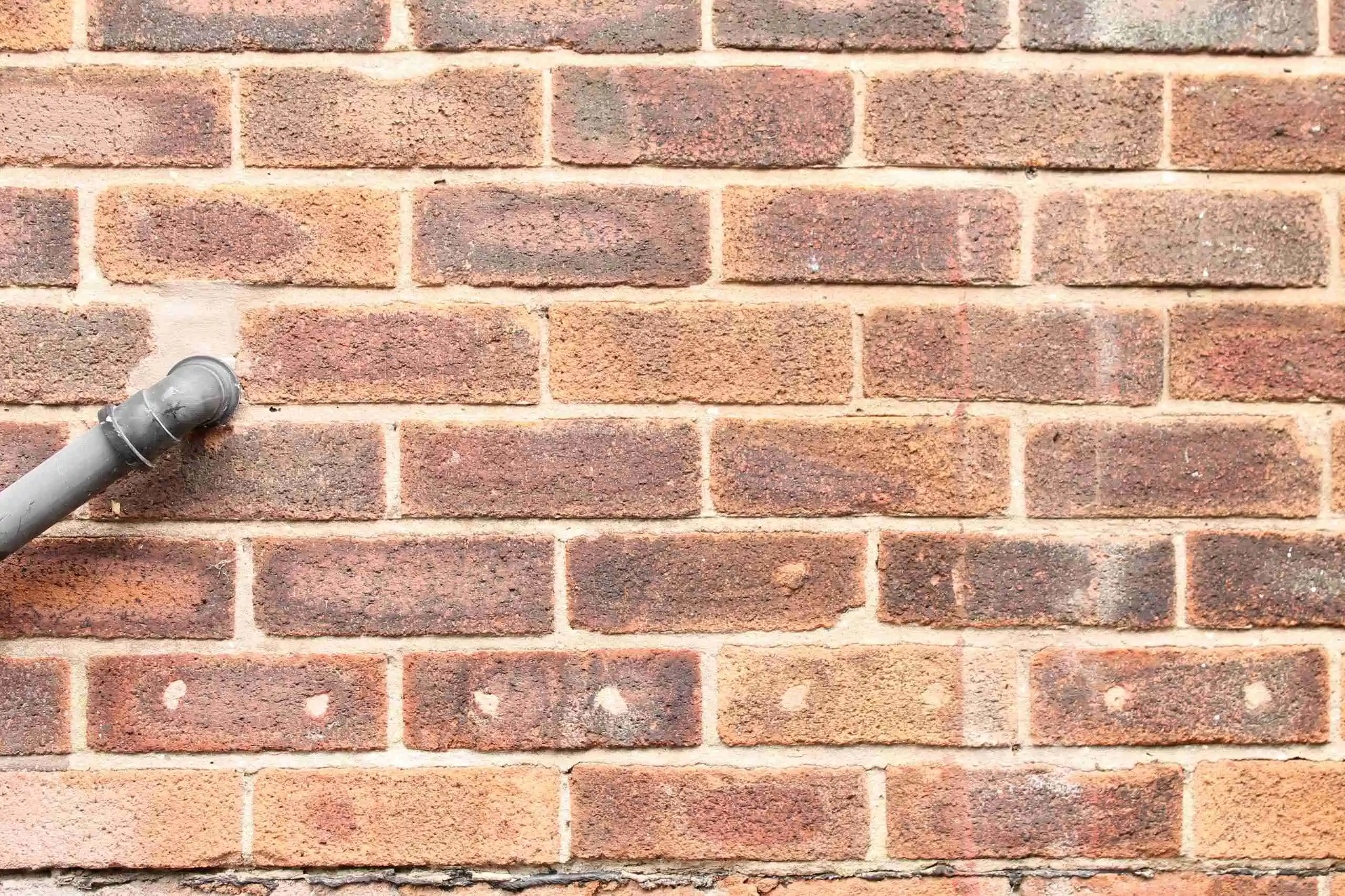 close up house wall that has had the cavity wall insulation holes filled in Cavity Wall insulation
